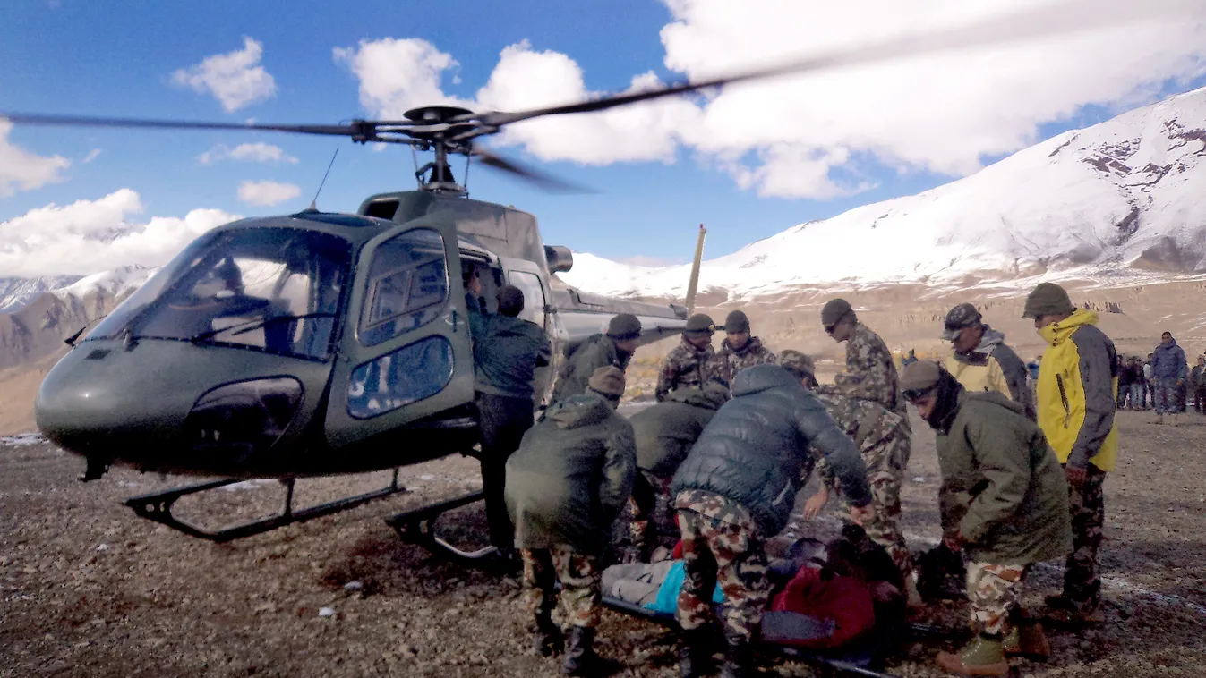 In this handout photograph released by the Nepal Army on October 15, 2014, an injured survivor of a snow storm is assisted by army personel into a Nepalese Army helicopter in Manang District, along the Annapurna Circuit Trek.  A snowstorm and avalanche in