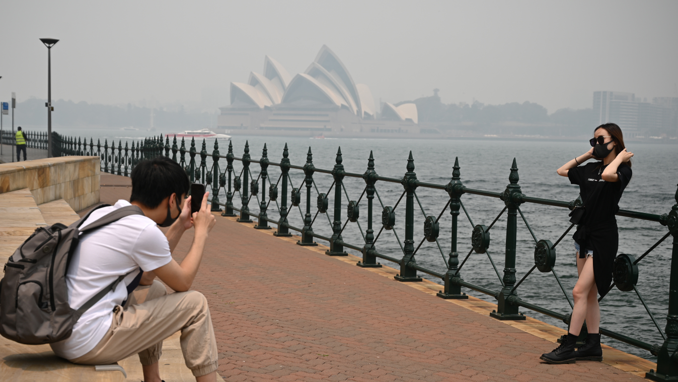 weather TOPSHOTS Horizontal Tourists wearing masks take photos as the Opera House (back, C) is enveloped in haze caused by nearby bushfires, in Sydney on December 10, 2019. - Toxic haze blanketed Sydney on December 10 triggering a chorus of smoke alarms t