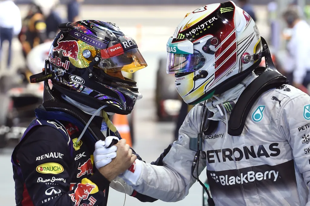 Red Bull Racing driver Sebastian Vettel of Germany (L) congratulates Mercedes driver Lewis Hamilton of Britain (R) on his victory after the Formula One Singapore Grand Prix in Singapore on September 21, 2014.    AFP PHOTO / TOSHIFUMI KITAMURA 