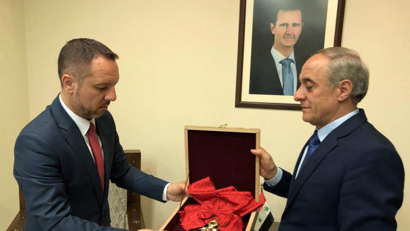 Horizontal A handout picture released on the Syrian President Facebook page on April 19, 2018 shows a representative of Syria's foreign affairs giving France's Legion d'Honneur Grand Croix (Great Cross) award to a representative from the Romanian embassy,