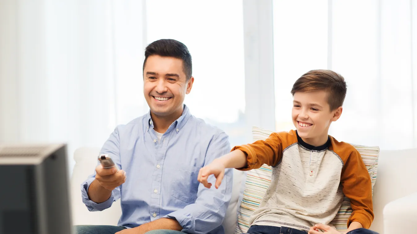 smiling father and son watching tv at home Leisure Activity Boys Men Males Remote Control Mature Adult Young Adult Child Smiling Pointing Sitting Watching Showing Movie Spectator Fun Southern European Descent Latin American and Hispanic Ethnicity Change C