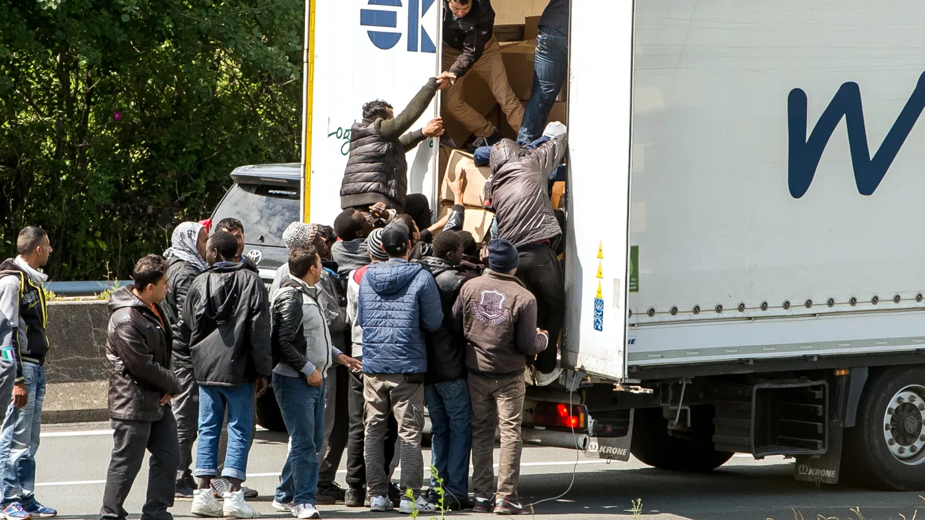 HORIZONTAL IMMIGRATION MIGRATION AND IMMIGRATION IMMIGRANT REFUGEE ILLEGAL IMMIGRANT MOTORWAY LORRY TRANSPORT Migrants climb in the back of a lorry on the A16 highway leading to the Eurotunnel on June 23, 2015 in Calais, northern France. Some of the thous