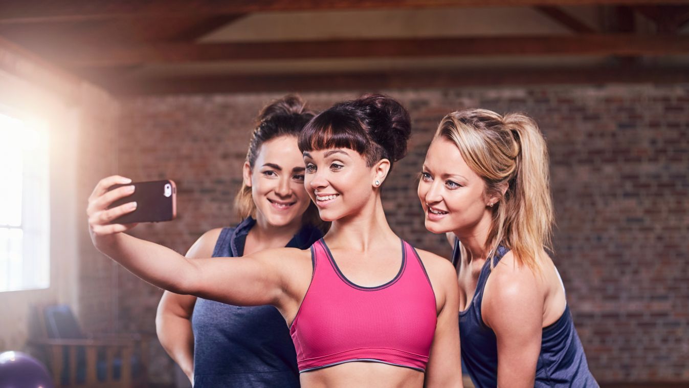 Fit young women in sports clothing taking selfie 20-24 years 25-29 years arms outstretched athletic bonding camera phone caucasian cell phone colour image confident day DEDICATION enjoyment exercise exercising fit fitness friendship gym happiness MEDICINE