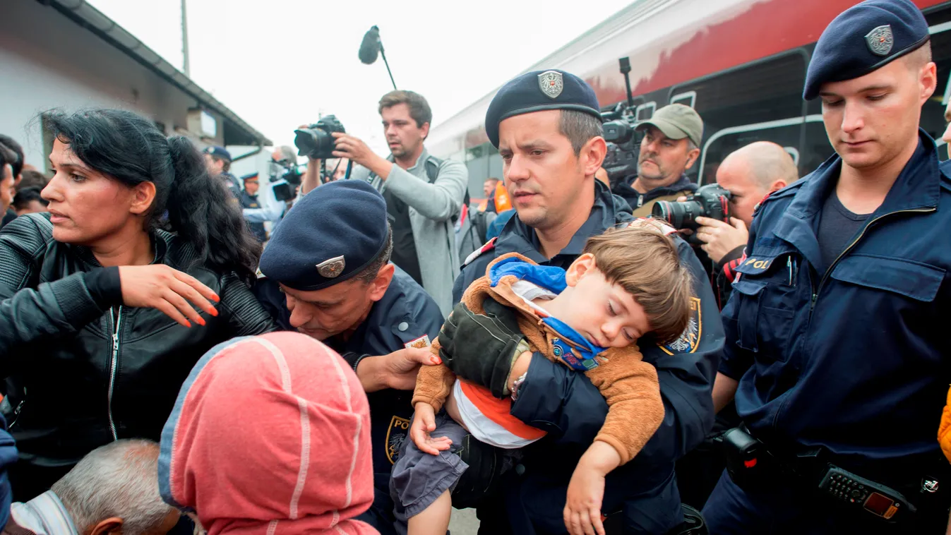 Austrian policemen are helping children and mothers to board a train in the Austrian village of Nickelsdorf on September 5, 2015 to take a train to Vienna.Thousands of migrants streamed into Austria from Hungary, in what Vienna called a "wake up call" for