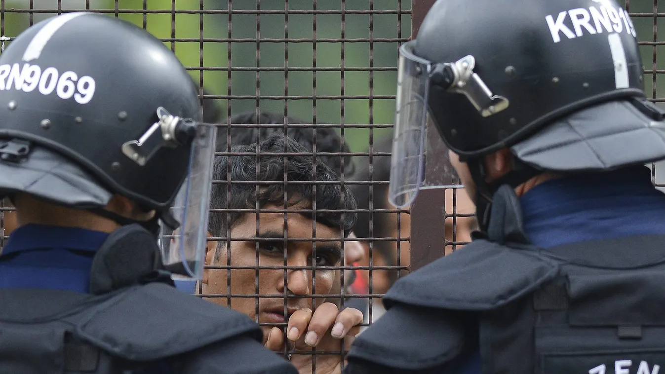 Debrecen, 2015. június 29.
Rendőrök állnak készenlétben a debreceni migrációs tábor bejáratánál 2015. június 29-én. A környékbeliek elmondása szerint a tábor mintegy száz lakója autókat rongált meg és kukákat gyújtott fel. A táborlakók kiabáltak a kiérkez