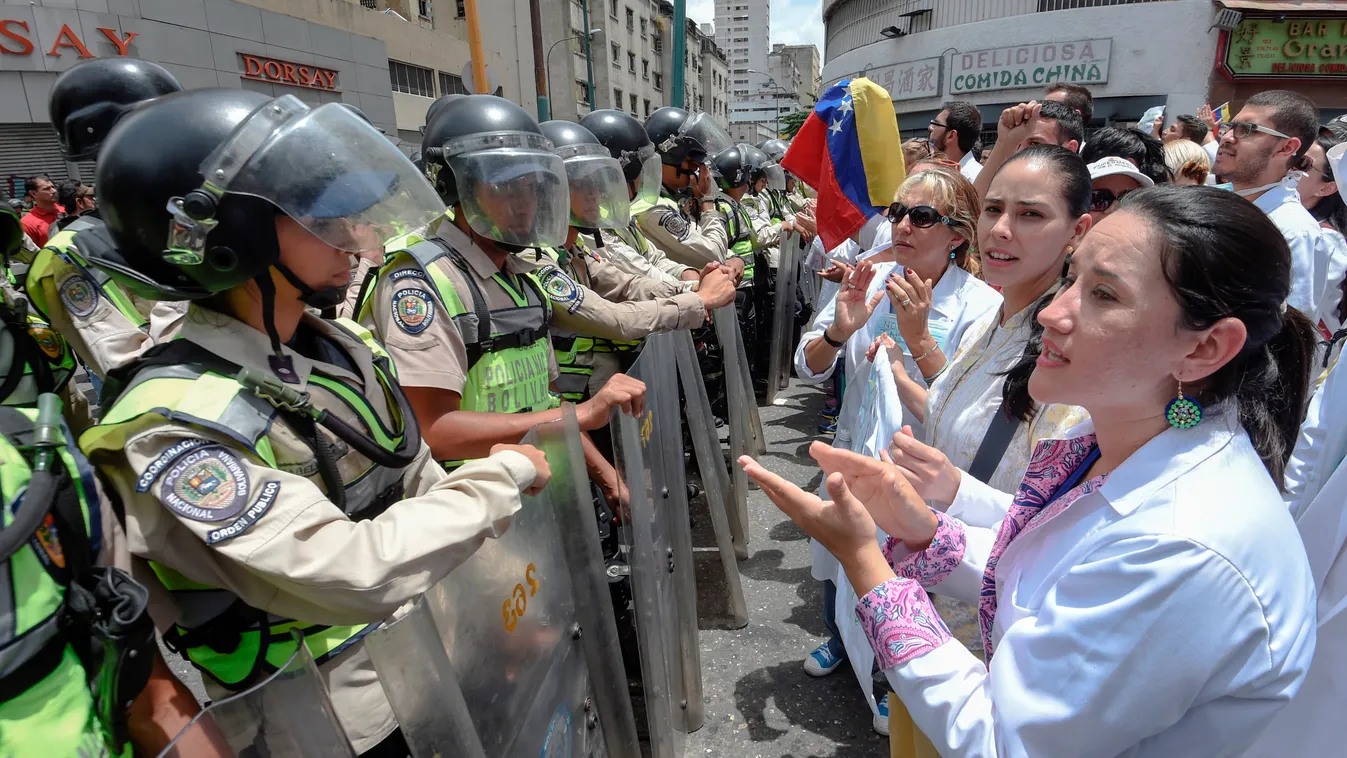 Horizontal Doctors chant slogans in front of a line of National Guard personnel in riot gear during a demonstration against the shortage in medicines and in rejection of the government of President Nicolas Maduro, in Caracas on May , 17, 2017.
Venezuela's