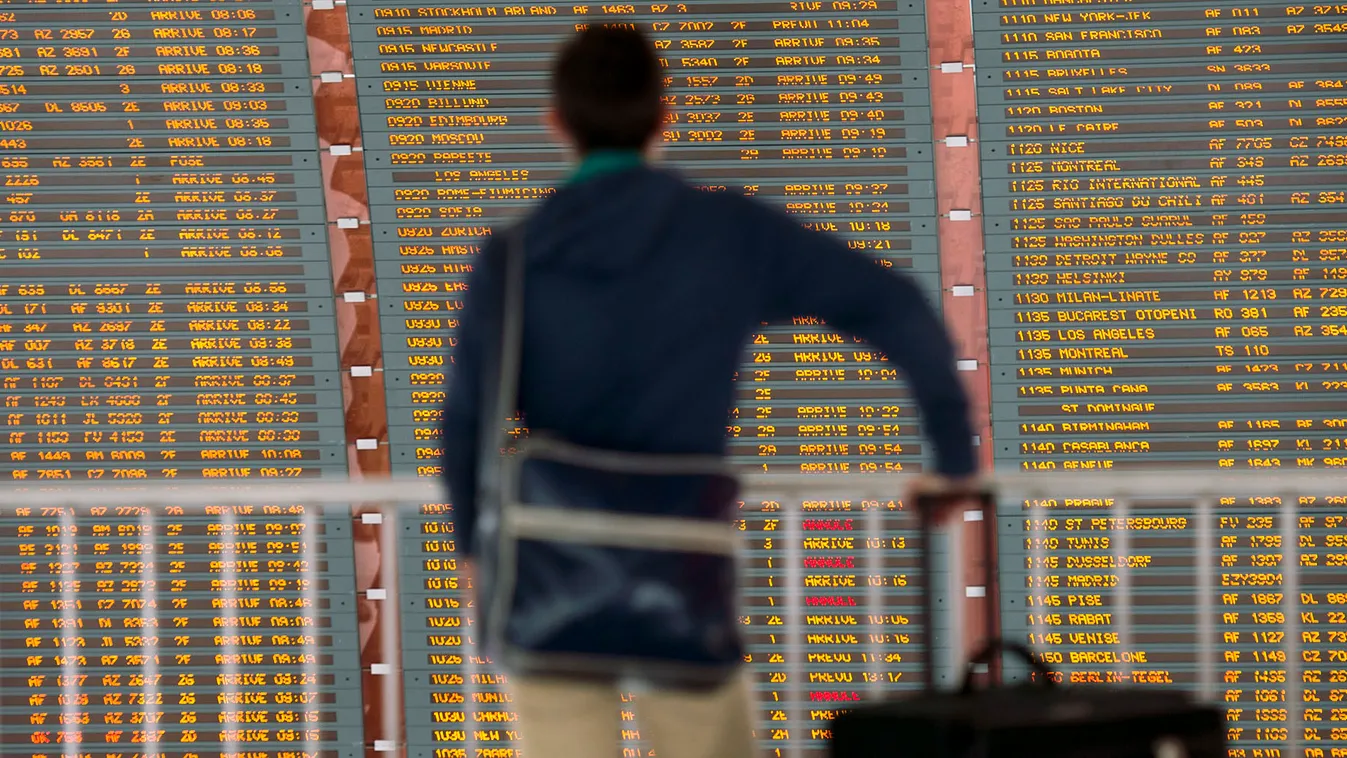 utasjogok késés esetém, egy utas a tájékoztató táblát figyeli a Charles de Gaulle reptéren