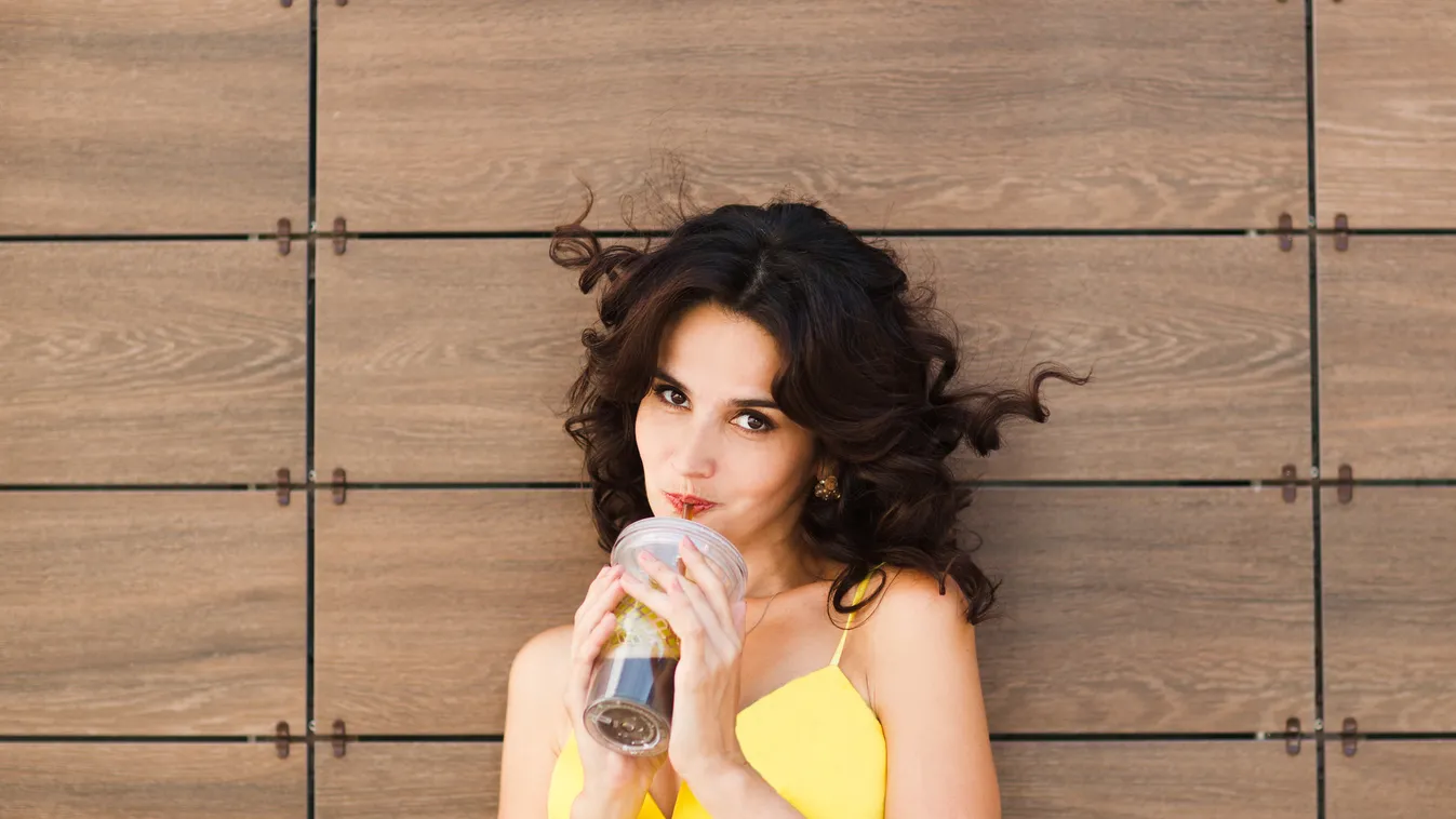 Pensive happy woman holding glass with tasty juice. Healthy Eating Portrait Women Females Dieting Smoothie City Life Thirsty Cola Cute Young Adult Smiling Handshake Looking Eating Fun Refreshment Healthy Lifestyle Cold - Temperature Heat - Temperature Ene