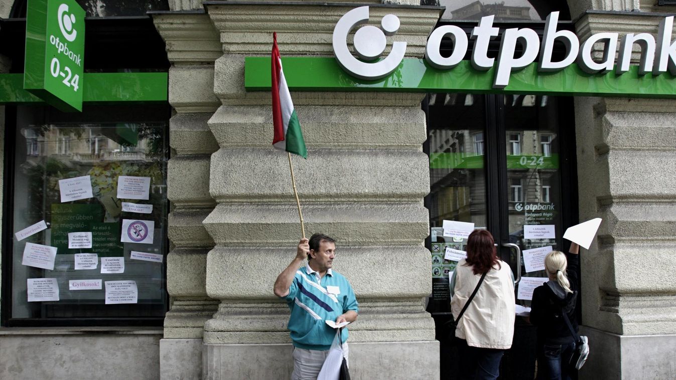 további százezrekre számíthatnak a devizahitelesek, Demonstrálók feliratokat ragasztanak fel egy OTP-bankfiók ablakára 2013. augusztus 27-én 