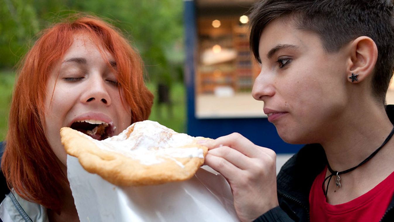 Lángossal eteti egymást két fiatal lány a Pannónia Fesztiválon, beleenni más ételébe