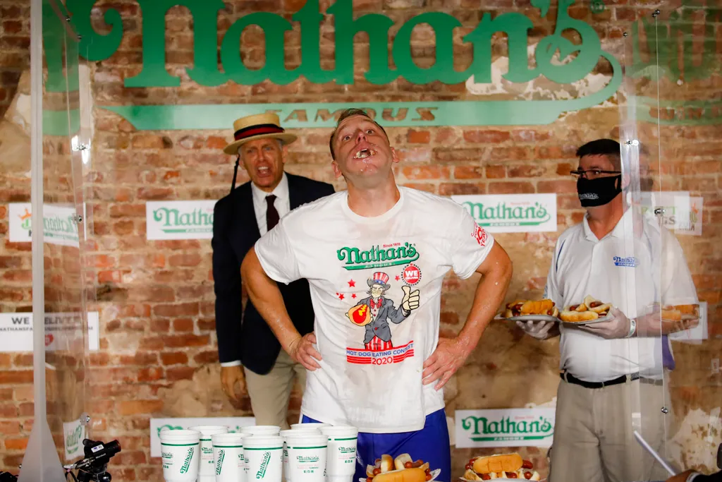 New York, 2020. július 4.
Joey Chestnut (k) úton a győzelem felé a július 4-i amerikai nemzeti ünnep alkalmából megrendezett Famous Nathan's hotdogevőversenyenNew York Brooklyn negyedében, 2020. július 4-én. Chestnut 75 hotdog felfalásával tizenharmadszor