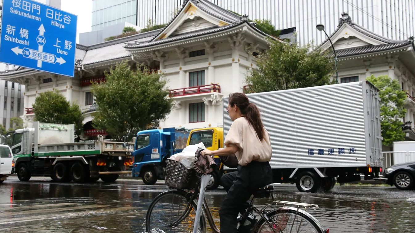 weather Horizontal A woman cycles through a flooded area in Tokyo on September 9, 2019. - A powerful typhoon with potentially record winds and rain battered the Tokyo region on September 9, sparking evacuation warnings to tens of thousands, widespread bla