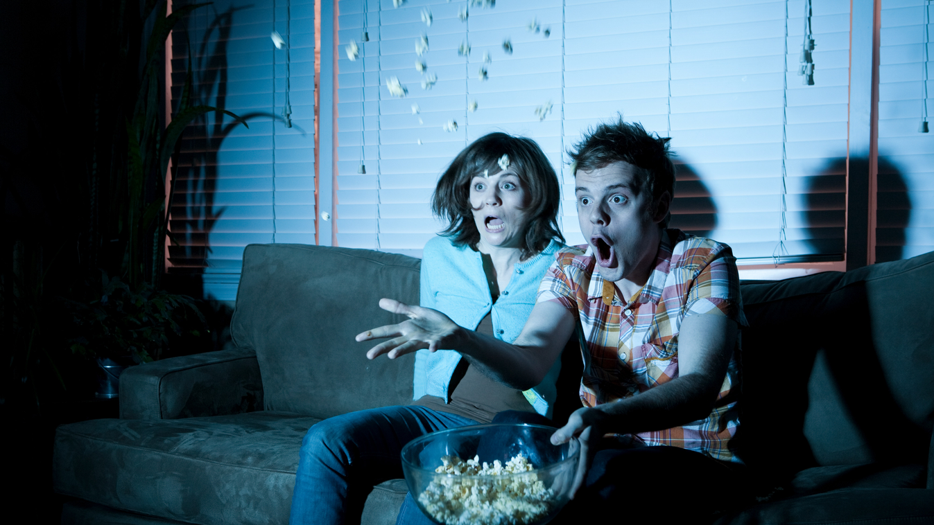 Young couple watching tv, man throwing popcorn throwing partner young couple couple two people popcorn snack food mid air movie film image manipulation vignette housing built structure house building structures house interior indoors living room action im