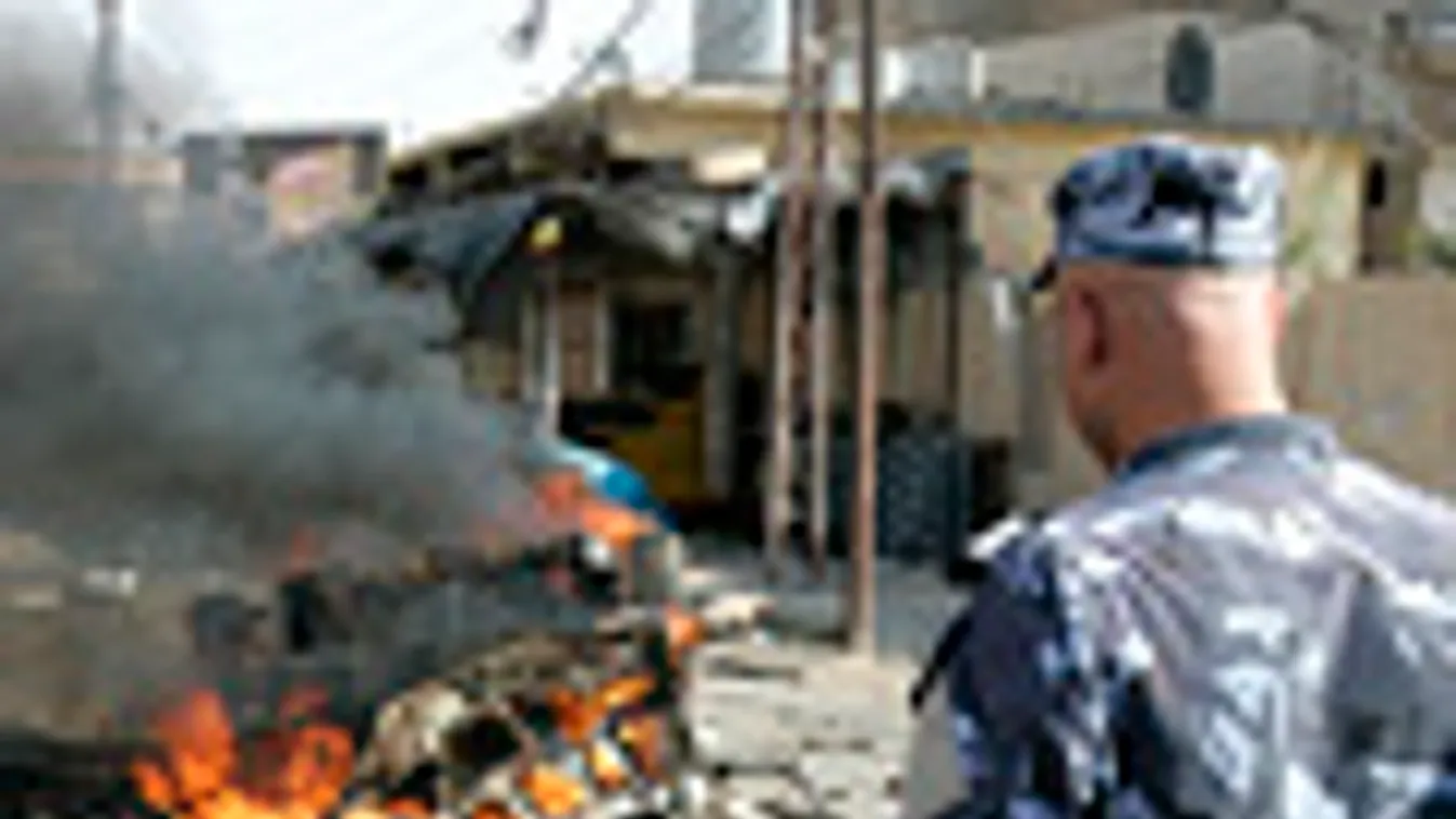 Irak, Bagdad, robbantásos merénylet, pokolgép, iraki katona nézi a lángoló autóroncsot Kirkukban 