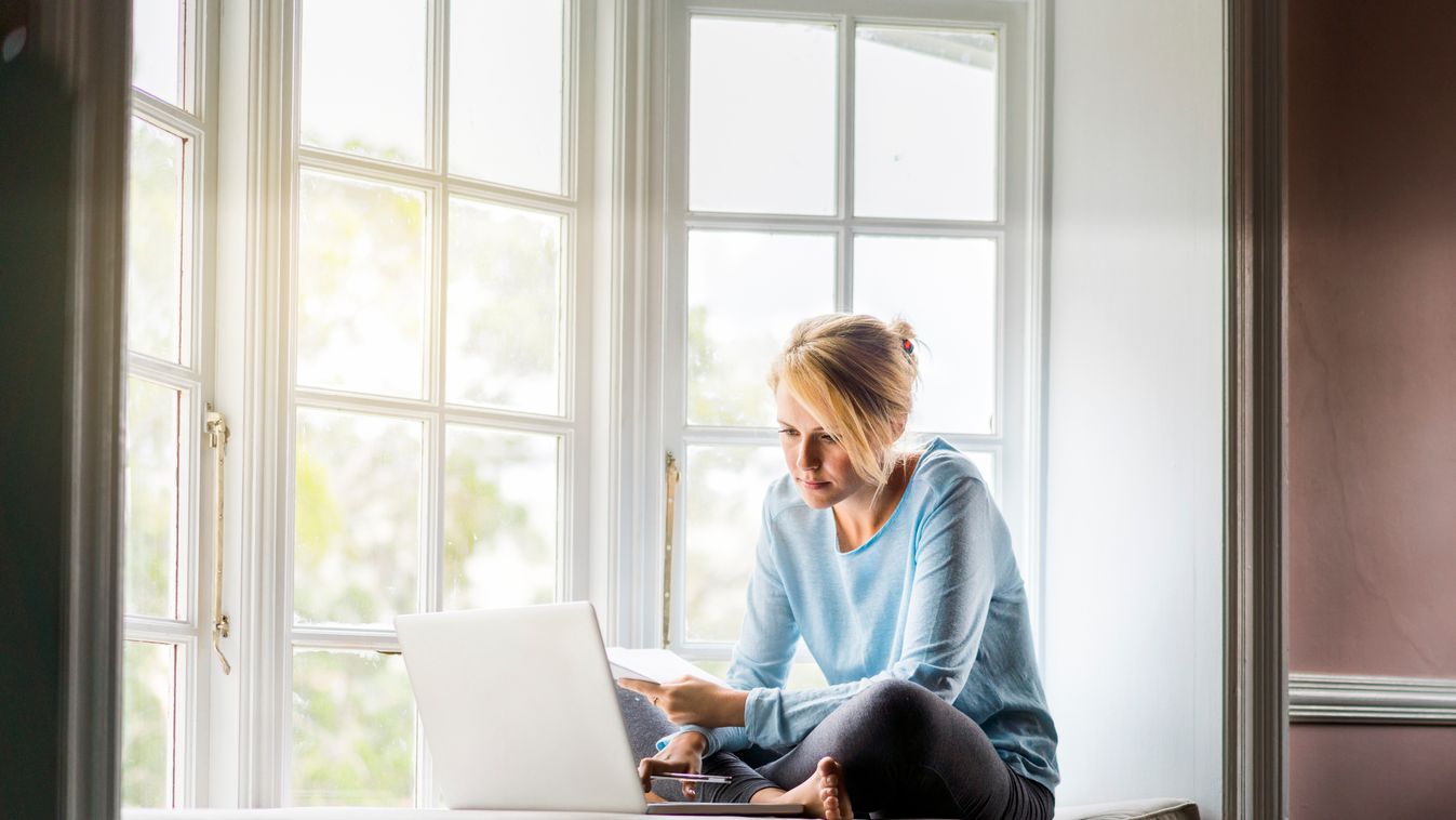 Young Woman using laptop on window sill Using Laptop Wireless Technology Brightly Lit Leisure Activity One Woman Only Only Women One Young Woman Only Only Young Women Young Women Women Females Comfortable Surfing the Net Mattress Paperwork Domestic Life W