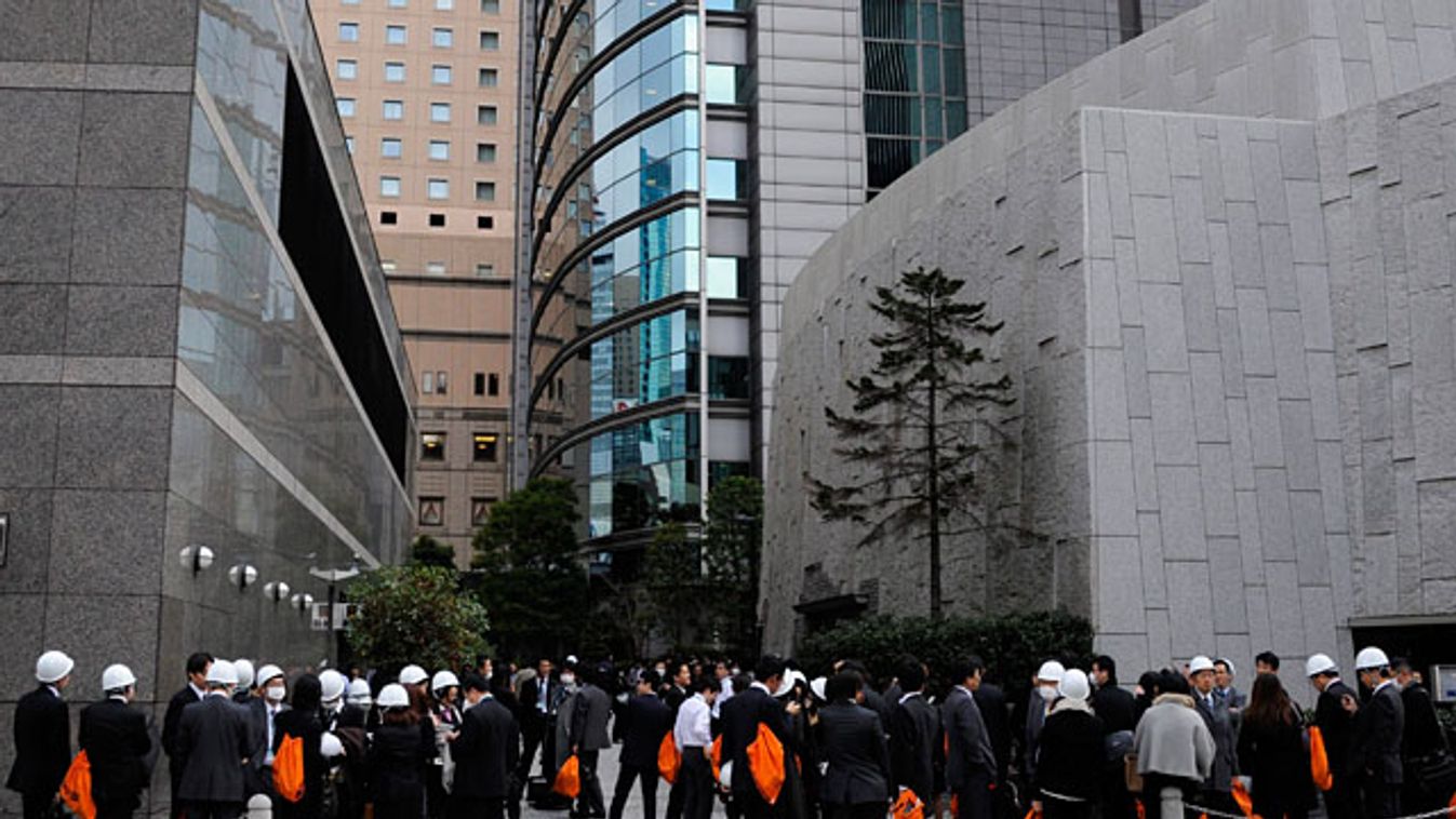 Egy tokiói irodaház dolgozói az utcán várakoznak, miután a Richter-skála szerinti 8,9-es erősségű földrengés volt Japán északkeleti partvidékén, ahol cunamit is indított 
