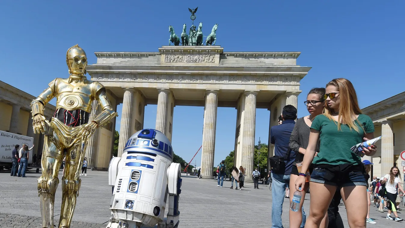 Járókelők nézik a Csillagok háborúja című mozifilmsorozat C-3PO és R2-D2  nevű szereplőinek viaszfiguráit a Brandenburgi kapu előtt Berlinben. A Madame Tussauds Berlin panoptikum időszaki kiállítást nyitott Csillagok háborúja címmel, melynek keretein belü