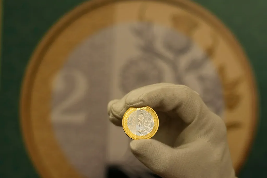 III. KÁROLY London, 2023. október 12.
A Brit Királyi Pénzverde egyik munkatársa mutatja az új kétfontos érmét a Londonban tartott sajtótájékoztatón 2023. október 12-én. A pénzverde tájékoztatása szerint ez év végén kezdik forgalomba bocsátani a III. Károl