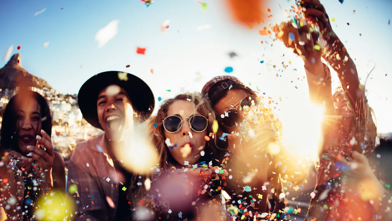 Teenager hipster friends partying by blowing colorful confetti from hands Boho Road Trip Retro Styled Adolescence Teenagers Only Leisure Activity Girls Teenage Girls Women Boys Men Group Of People Celebration Youth Culture Lens Flare Confetti 20-29 Years 