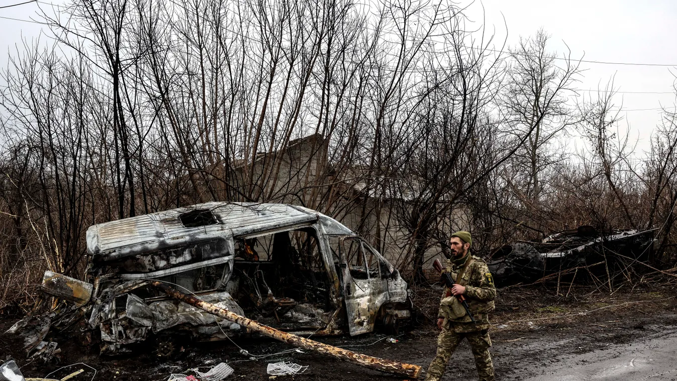 HORIZONTAL war conflict TOPSHOTS A Ukrainian soldier patrols next to a burned vehicle in the village of Lukianivka near Kyiv on March 30, 2022. (Photo by RONALDO SCHEMIDT / AFP) Ukrán válság 2022, ukrán, orosz, háború, orosz-ukrán háború, ukrán konfliktus