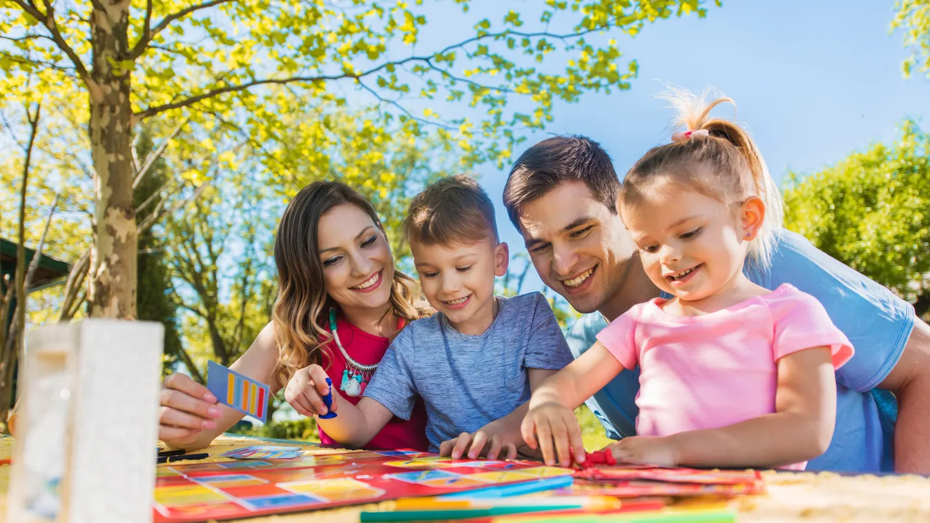 Happy family spending a day outdoors and playing board game. Family Bonds Leisure Activity Girls Women Females Boys Men Males Four People Small Group Of People Group Of People Weekend Activities Young Adult Adult Child Smiling Sitting Playing Playful Teac