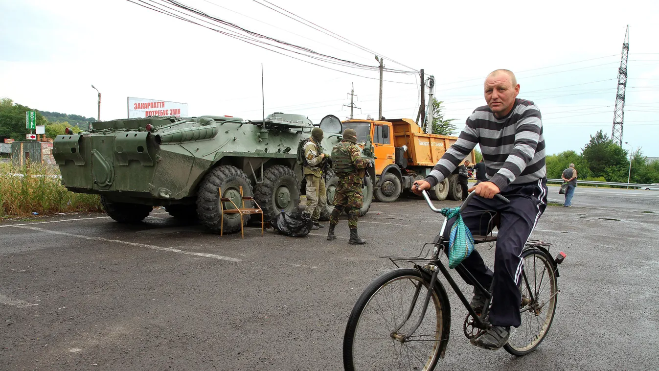 Munkács, 2015. július 13.
Egy kerékpáros a kommandósok ellenőrző pontja mellett Munkácson 2015. július 13-án. Tűzharc tört ki július 11-én a város egyik sportlétesítménynél a Jobboldali Szektor (PSZ) szélsőséges szervezet fegyveresei és az ukrán parlament