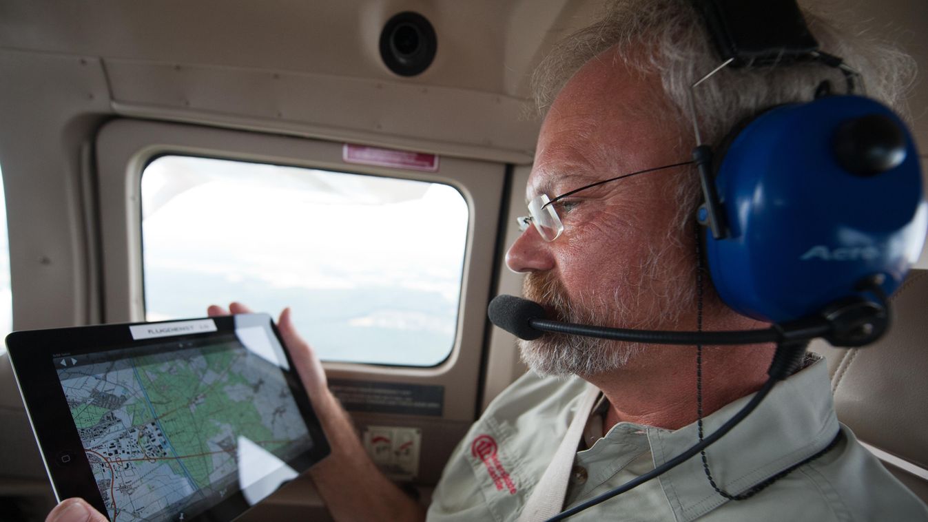 Forest ranger Rolf Sund looks at a tablet compter while flying in a Cessna 206 for a surveillance flight above Lueneburg, Germany, 24 July 2013. On demand of the police headquarters of Lueneburg, the flight service of the state fire brigade association Lo