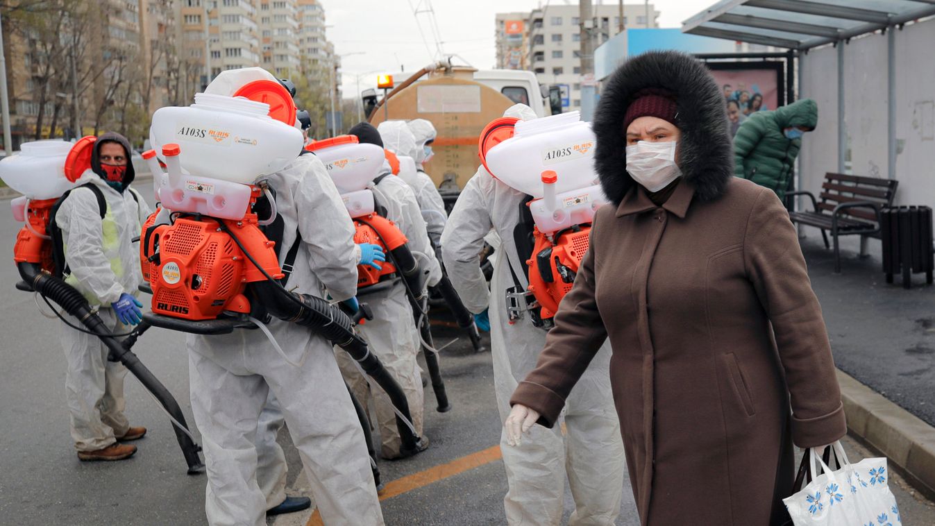 Az új koronavírus járványa megfékezésének érdekében egy bukaresti utcát fertőtlenítenek védőruhás városi alkalmazottak 2020. március 31-én. 