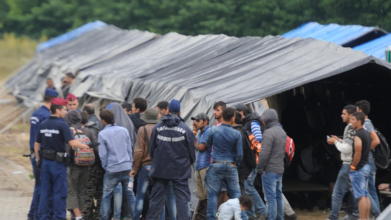 Röszke, 2015. június 25.
Rendőrök elfogott határsértőkkel beszélgetnek a röszkei hangárnál 2015. június 25-én. Az épületben és a szomszédságában felállított sátrakban őrzik az első 24 órában azokat a határsértőket, akiket Csongrád megyében fogtak el. A re
