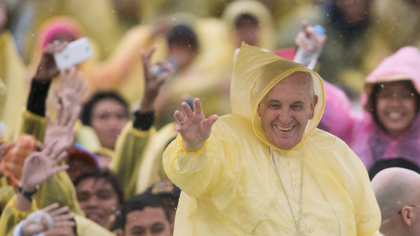 Pope Francis (R) wears a plastic poncho as he waves to well wishers after a mass in Tacloban on January 17, 2015. Pope Francis will spend an emotional day in the Philippines on January 17 with survivors of a catastrophic super typhoon that claimed thousan