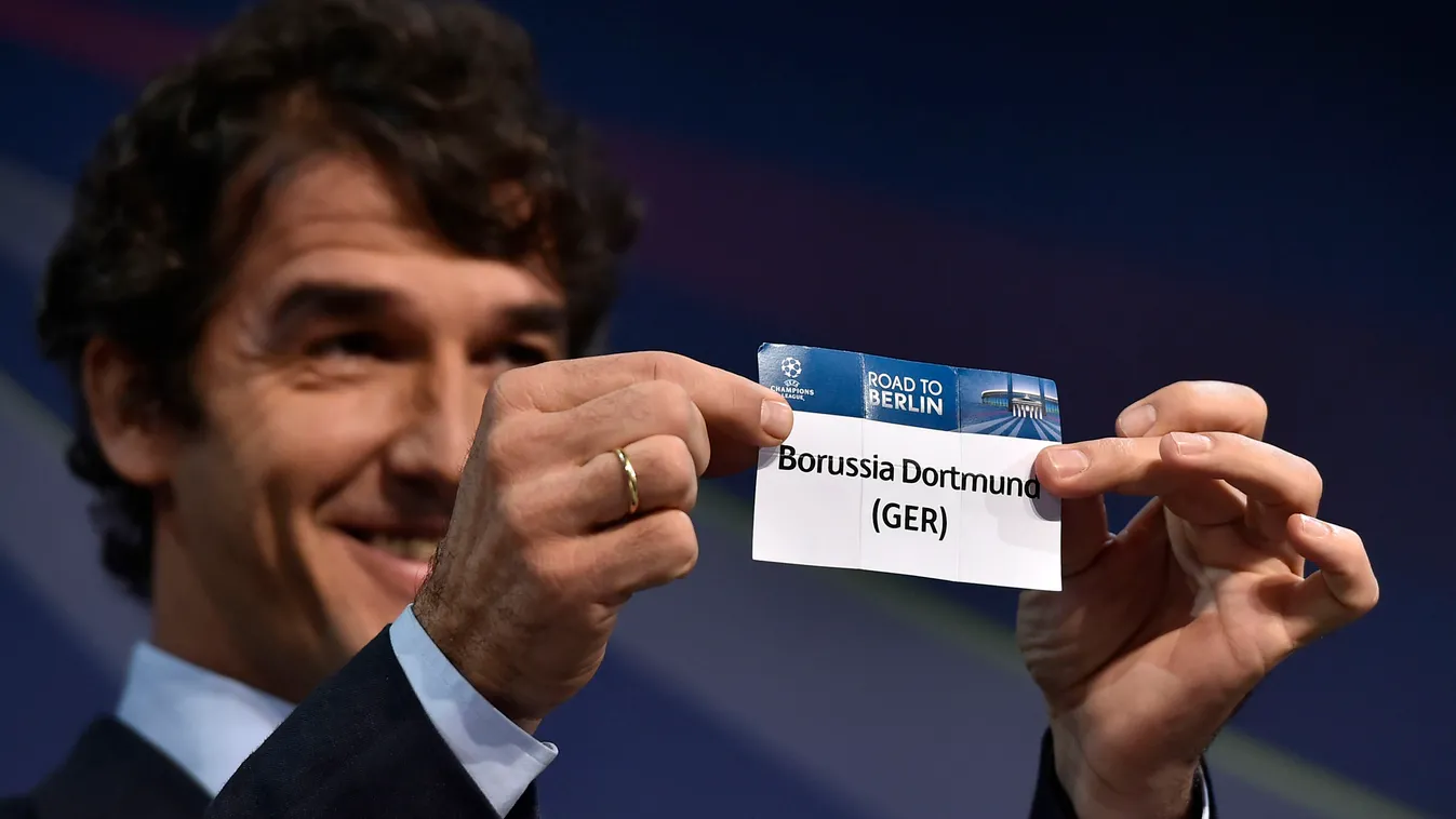 ambassador for the UEFA Champions League final in Berlin Karl-Heinz Riedle presents the name Borussia Dortmund during the draw for the UEFA Champions League round of 16 on December 15, 2014 at the UEFA headquarters in Nyon.  AFP PHOTO / FABRICE COFFRINI 