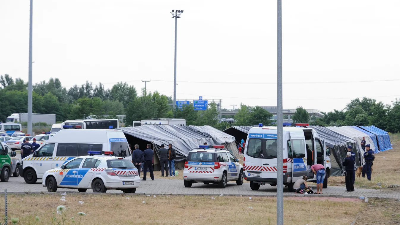 Röszke, 2015. június 25.
Rendőrségi járművek a röszkei hangárnál 2015. június 25-én. Az épületben és a szomszédságában felállított sátrakban őrzik az első 24 órában azokat a határsértőket, akiket Csongrád megyében fogtak el. A rendőrség bevetési osztályán