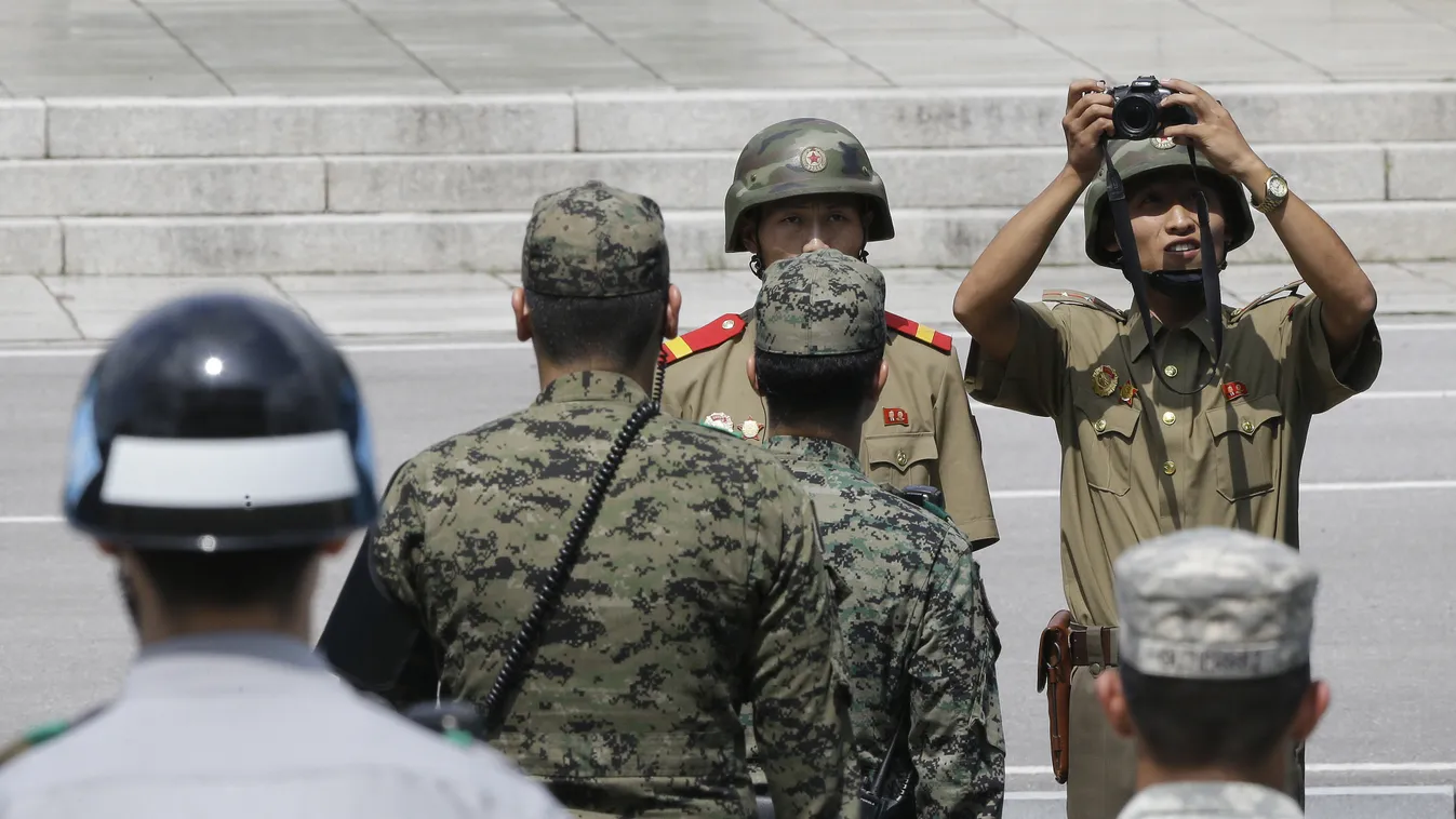 A North Korean soldier (R) takes photos of the south side as South Korean and US soldiers stand guard after a ceremony to commemorate the 62nd anniversary of the Korean War Armistice Agreement that ended the Korean War at the border village of Panmunjom, 