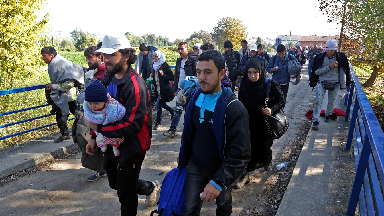 A migrant carrying his child walks with around 2000 migrants who arrived by train and walk near the border town of Kljuc Brdovecki, on October 24, 2015, to cross the Croatia-Slovenia border. Crowds of refugees and other migrants camp by roads in western B