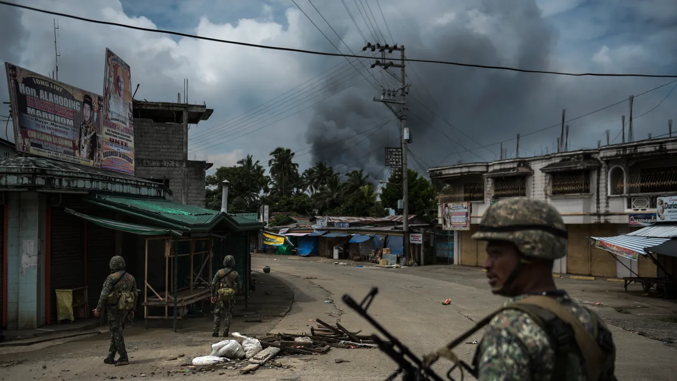 Philippine Troops Battle To Retake Marawi Conflict Human Rights Military Politics Terrorism MARAWI, PHILIPPINES - JUNE 06: Soldiers patrol a street as smoke billows from a fire caused by heavy gunfights and aerial strikes on June 6, 2017 in Marawi city, P