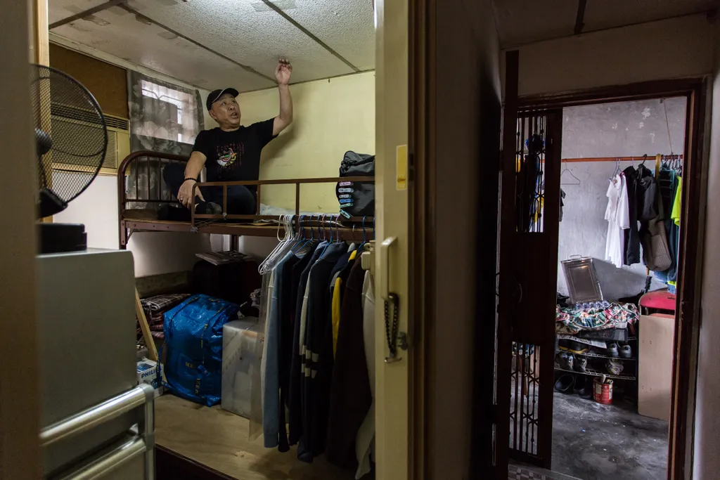 social Horizontal This picture taken on April 18, 2016 shows David Yu touching the ceiling as he sits on his bed in his "cubicle" flat, built within a subdivided Hong Kong 