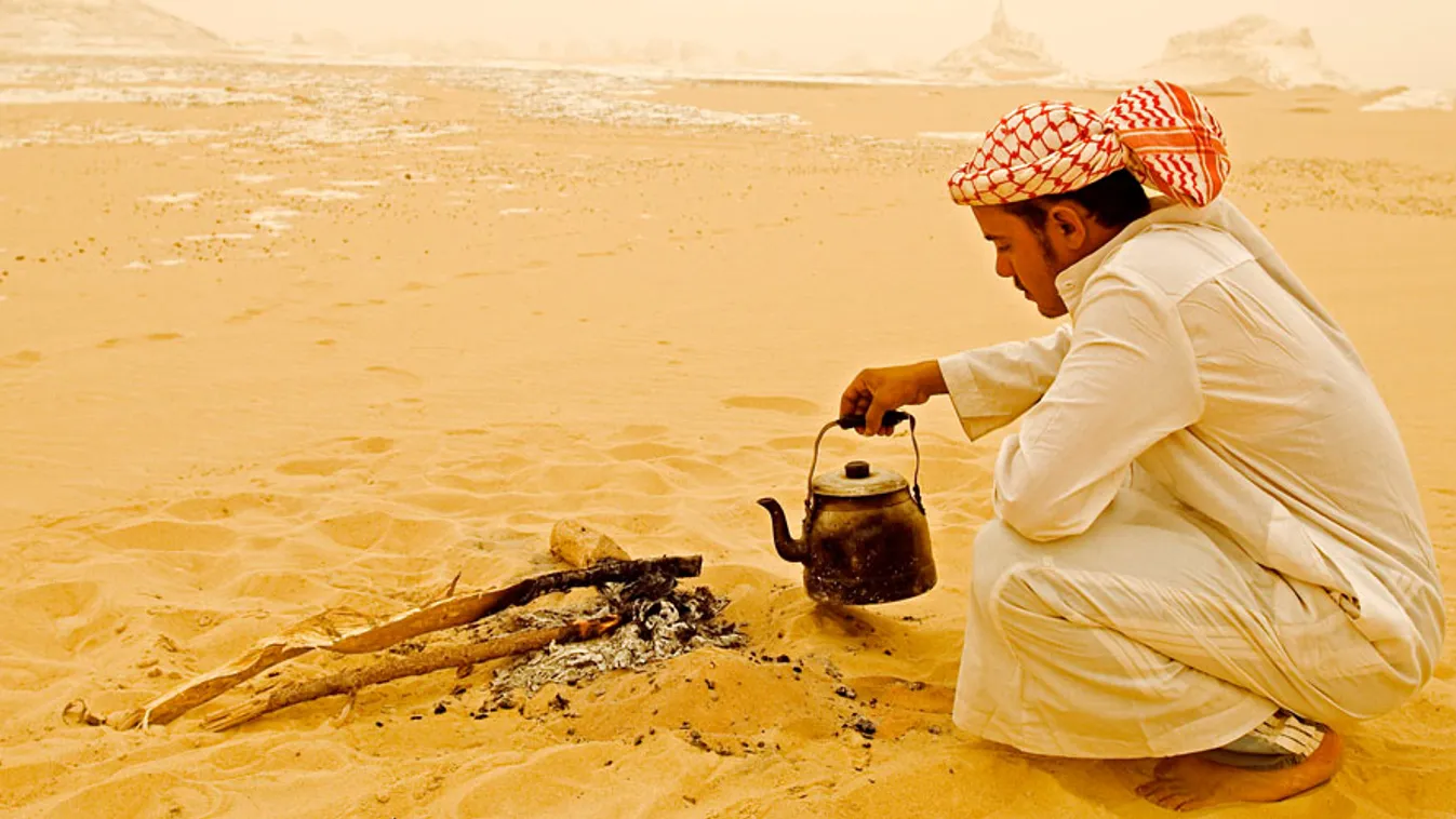 Forró italok a kénikulában, egy férfi teát készít a sivatagban Egyiptomban
