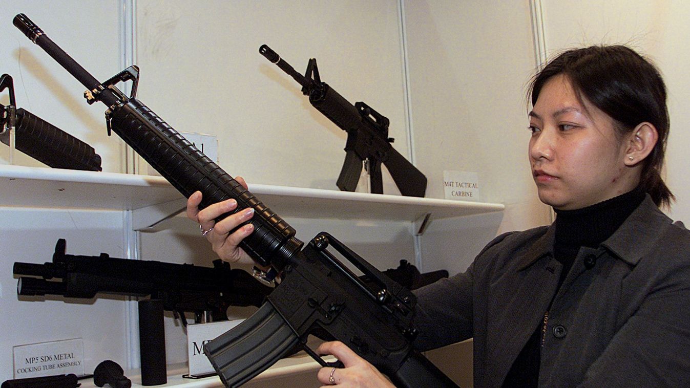 Horizontal GUN FAIR TOY Yan Yip, General manager of Yick Fung Ltd, holds up a replica of a M16 assault rifle at their booth at the Hong Kong's Toys & Fair, 08 January 2002.  The fair, being held at the Hong Kong Convention and Exhibition Centre opened tod