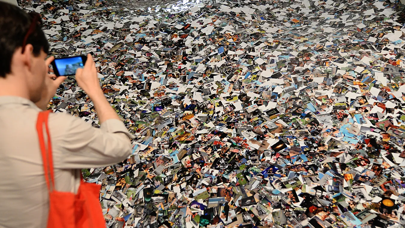 A fotográfia napjára
A visitor takes pictures of photographs of Dutch photographer Erik Kessels piled on the floor, on July 1, 2013 during the 4 