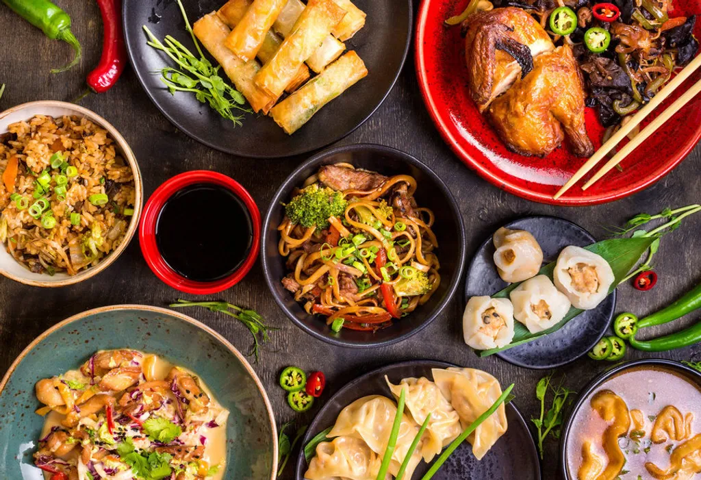 Assorted Chinese food set. Chinese noodles, fried rice, dumplings, peking duck, dim sum, spring rolls. Famous Chinese cuisine dishes on table. Top view. Chinese restaurant concept. Asian style banquet 