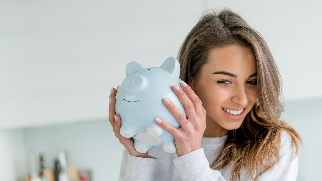 Happy woman saving money in a piggybank Portrait Women Females Banking Savings Coin Bank Piggy Bank Currency Home Finances Young Adult Smiling Caucasian Ethnicity Latin American and Hispanic Ethnicity One Person Strategy Planning Business Finance Lifestyl