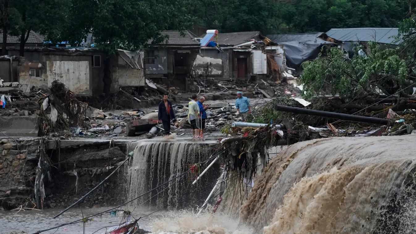 Peking, 2023. július 31.
Emberek nézik a Doksuri tájfun okozta heves esőzések által elmosott utak egyikének maradványait a nyugat-pekingi Mentugu kerületben 2023. július 31-én. Több mint 31 ezer embert evakuáltak otthonaikból a kínai fővárosban, miután a 