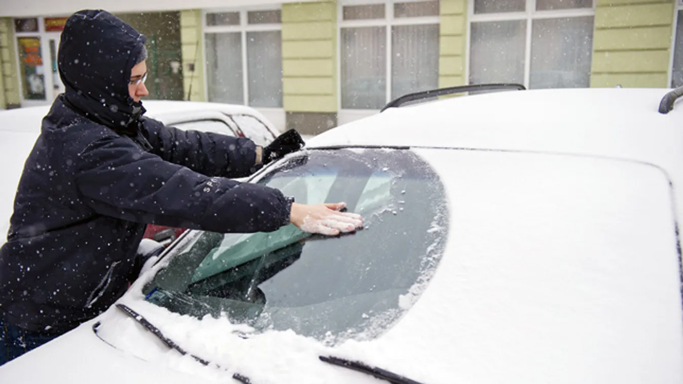 Egy nő takarítja autója behavazott szélvédőjét Orosháza belvárosában. Békés megyébe -12 Celsius-fokos hideg és orkán erejű szél kíséretében érkezett meg a havazás 