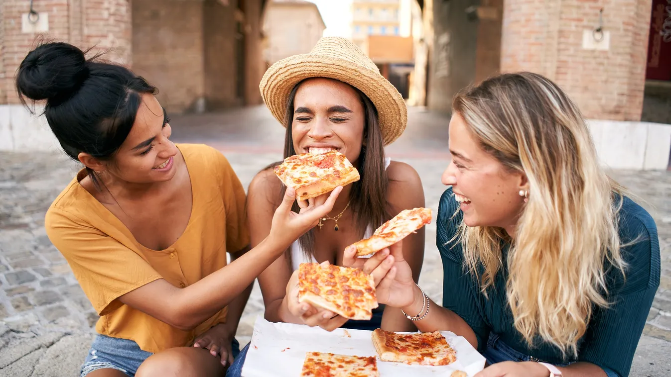 Happy,Girlfriends,Eating,Pizza,Street,Food,At,The,City.,Female lunch,friendship,woman,fast food,student,happy,young adult 