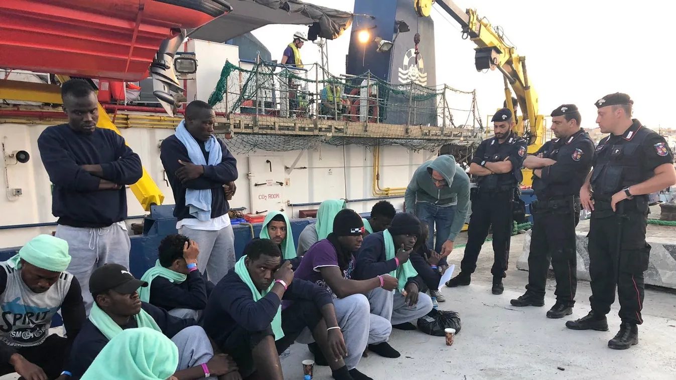 Lampedusa, 2019. június 29.
Európába igyekvő illegális bevándorlók ülnek a rakparton rendőri őrizetben Lampedusán 2019. június 29-én, miután az őket szállító Sea Watch 3, a Sea-Watch nevű német nem kormányzati szerv holland bejegyzésű hajója kikötési enge