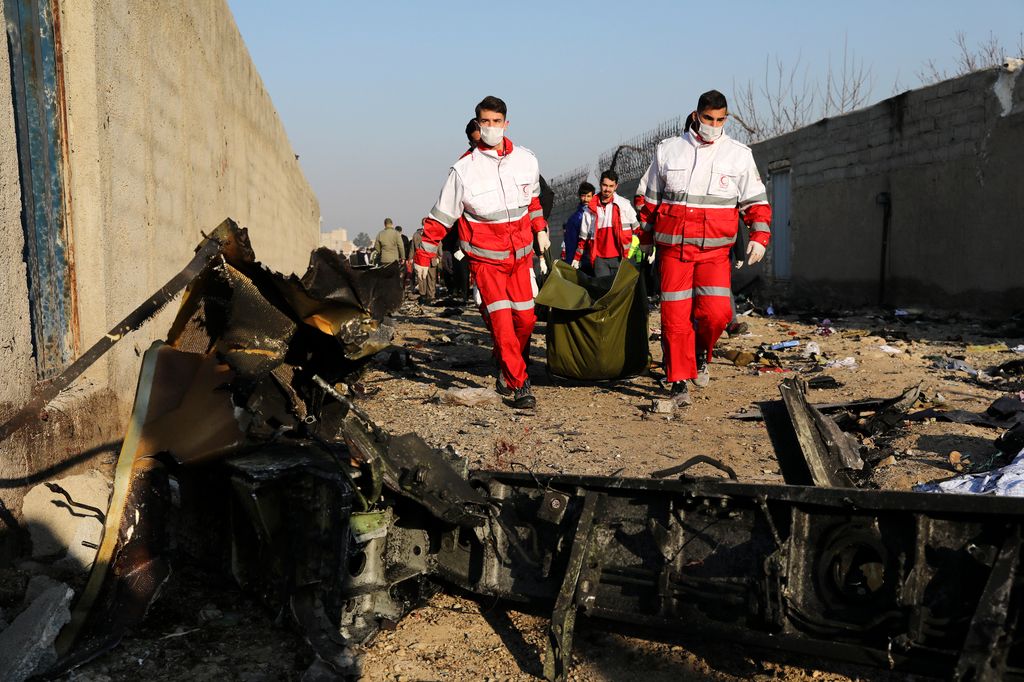 Hullazsákot visznek a Vörös Félhold segélyszervezet munkatársai a lezuhant repülőgép roncsdarabjainál. 