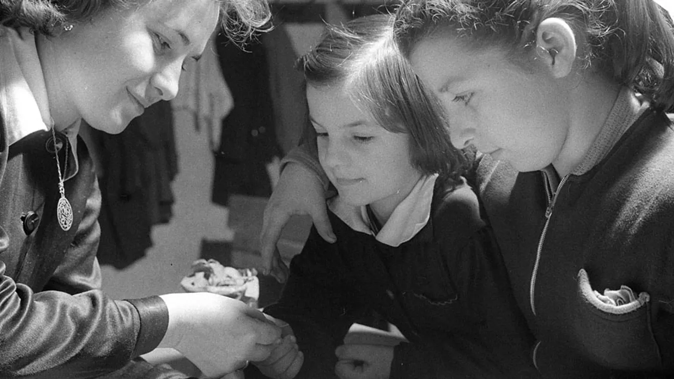 Détár Mihályné tanítónő takarékbélyeget ad Fábián Évának és Kiss Erzsébetnek, a vezsenyi általános iskola tanulóinak 1961-ben