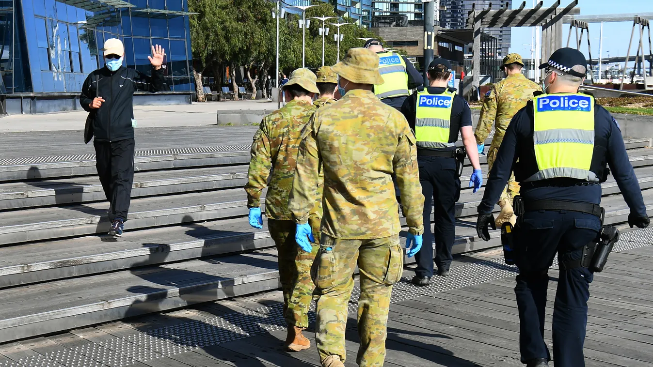 virus Horizontal A man waves to a group of police and soldiers patrolling the Docklands area of Melbourne on August 2, 2020, after the announcement of new restrictions to curb the spread of the COVID-19 coronavirus. - Australia on August 2 introduced swee