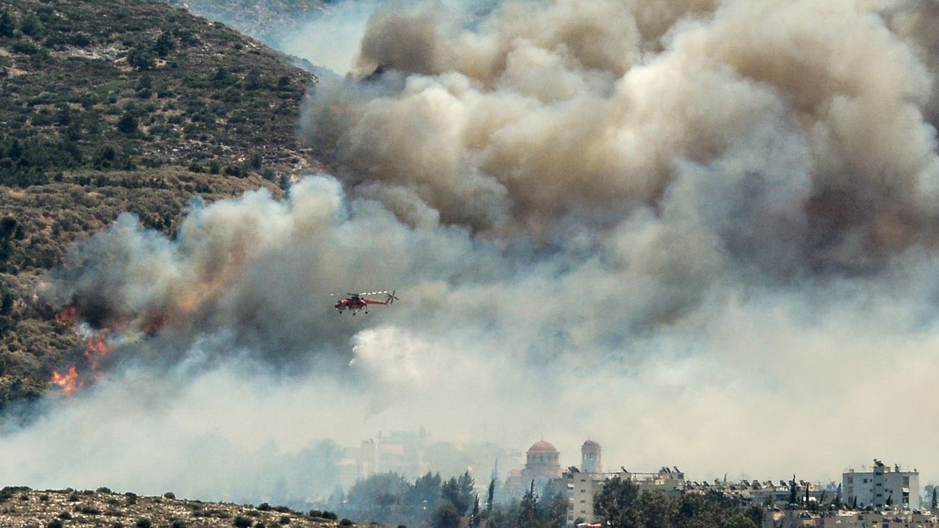 An helicopter of firefighters fly over smokes billowing over Athens, on July 17, 2015 as firemen were battling a brush fire in northeastern Athens and another wildfire in the southern Pelopponese peninsula that prompted the evacuation of five villages. Mo