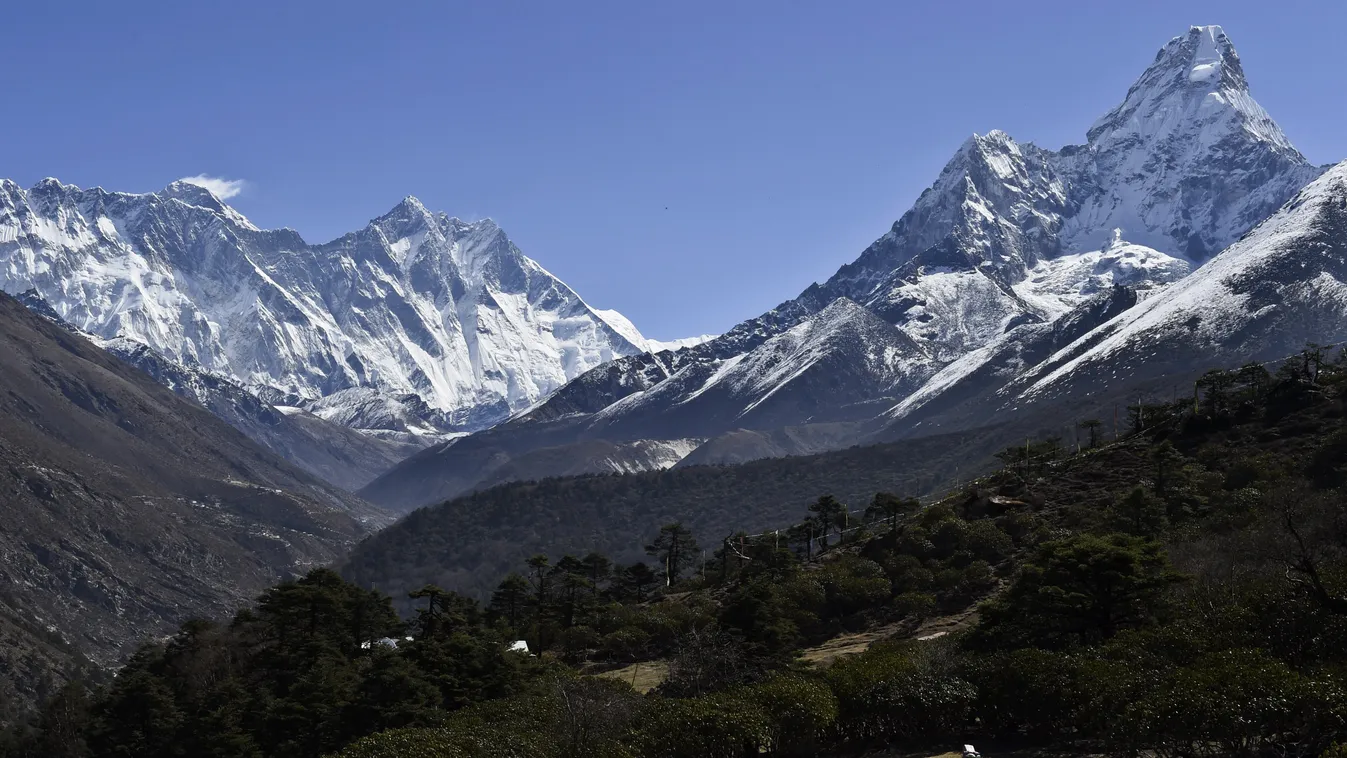 (FILES) In this file picture taken on April 20, 2015, a Nepalese porter carries a load as he walks on a path way below some of the highest peaks on as earth Mount Everest (L) towers all else deep and high into the Kumbh region of northeastern Nepal. The w